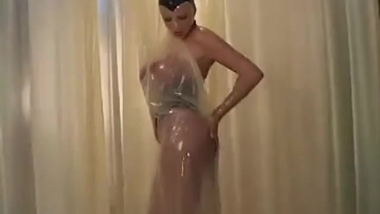 Transparent rubber girl with big boobs poses and masturbates in room with rubber curtains